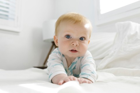 Baby boy (6-11 months) lying on bed