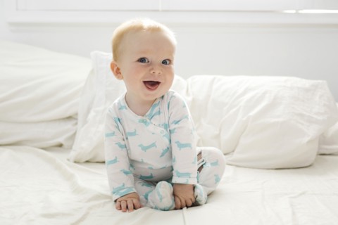 Baby boy (6-11 months) lying on bed