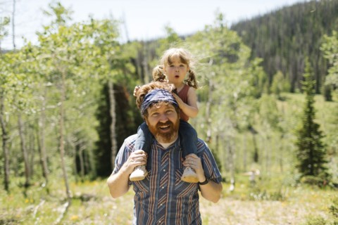 USA, Utah, Uinta National Park, Portrait of smiling man carrying daughter (2-3) on shoulders in landscape
