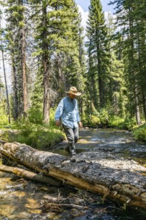 USA, Idaho, Sun Valley, Man crossing river in forest
