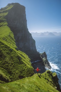 Denmark, Faroe Islands, Klaksvik, Trollanes, Woman standing on cliff and looking at ocean