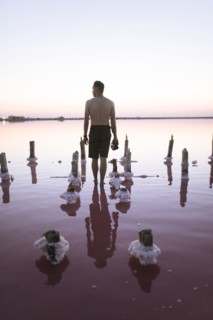 Ukraine, Crimea, Man standing in salt lake and holding camera