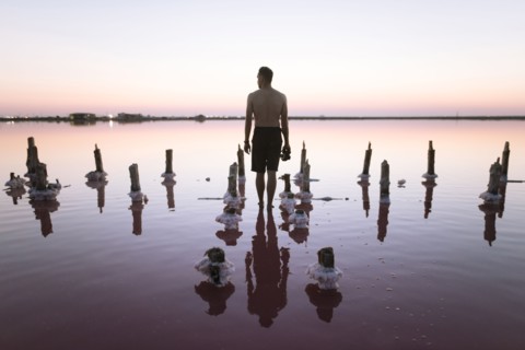 Ukraine, Crimea, Man standing in salt lake and holding camera