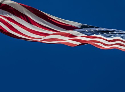 American flag blowing in wind against blue sky
