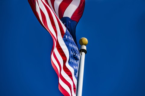 American flag blowing in wind against blue sky