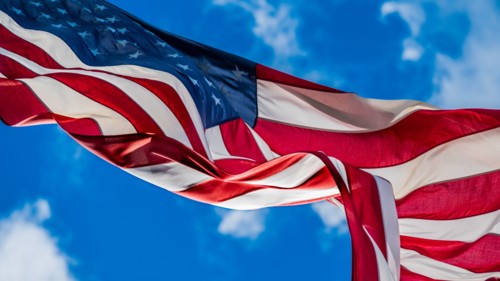 American flag blowing in wind against sky
