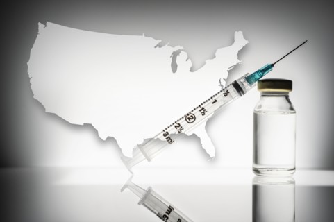 Studio shot of laboratory vial and syringe with USA shape in background
