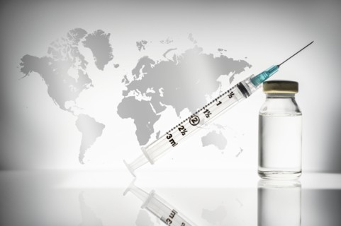 Studio shot of laboratory vial and syringe with world map in background