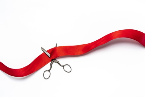 Studio shot of old fashioned scissors cutting red ribbon