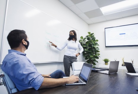 Businesswoman in face mask giving presentation in office