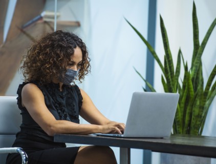 Businesswoman wearing face mask working on laptop at desk in office