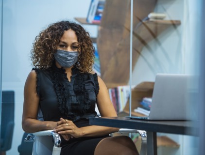 Portrait of businesswoman wearing face mask sitting at desk in office