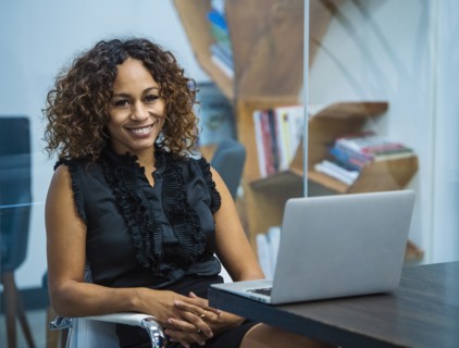 Portrait of smiling businesswoman sitting at desk in office