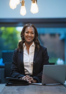 Portrait of smiling businesswoman sitting at desk with laptop in office