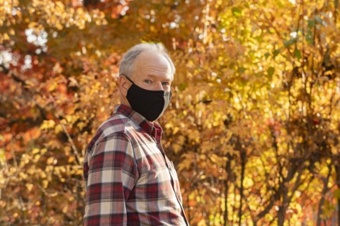 Portrait of senior man wearing Covid protective mask outdoors in fall