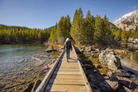 Senior woman walking on wooden path over Taggart Lake in Grand Teton National Park