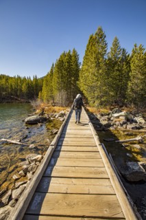 Senior woman walking on wooden path over Taggart Lake in Grand Teton National Park