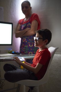 Mother watching son (8-9) during e-learning at home due to Covid-19 lockdown