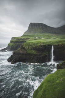 Coastline with Mulafossur Waterfall falling into Atlantic Ocean