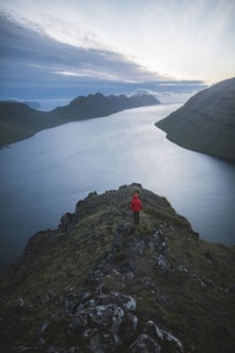 Woman standing on top of Klakkur mountain over sea and looking at view