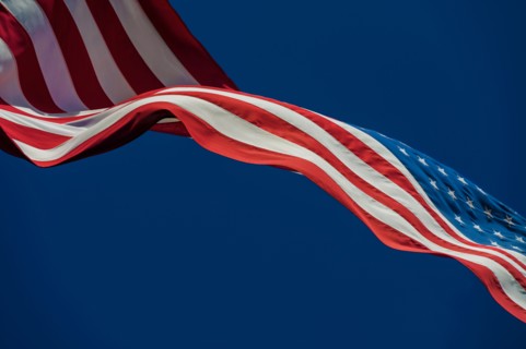 American flag blowing in wind against blue sky