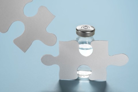 Vial of Covid-19 vaccine behind jigsaw puzzles