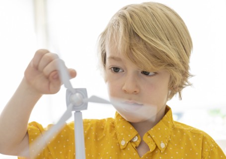 Boy (6-7) playing with wind turbine model