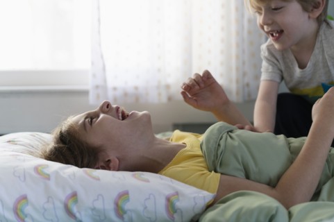 Brother (6-7) and sister (8-9) playing on bed