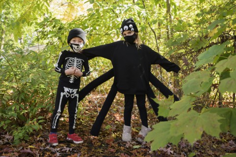 Girl (8-9) and boy (6-7) wearing Halloween costumes in forest
