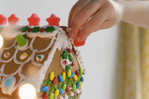 Hand decorating gingerbread house cake