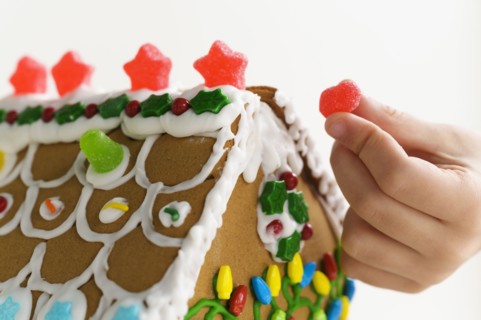 Hand decorating gingerbread house cake