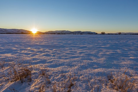 Sun setting over snowy field
