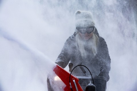 Senior woman clearing snow using snowblower