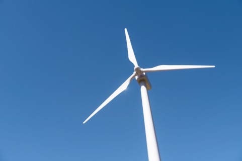 Low angle view of wind turbine against blue sky