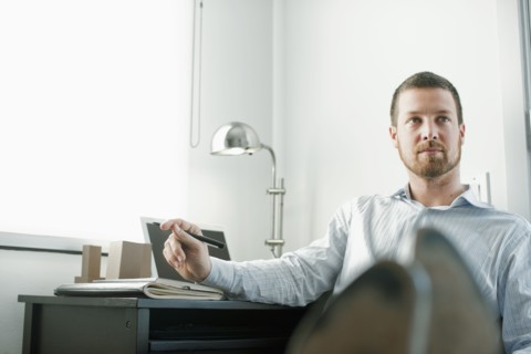 Caucasian businessman sitting at desk with feet up