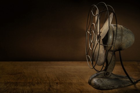 Old metal electric fan on wooden table
