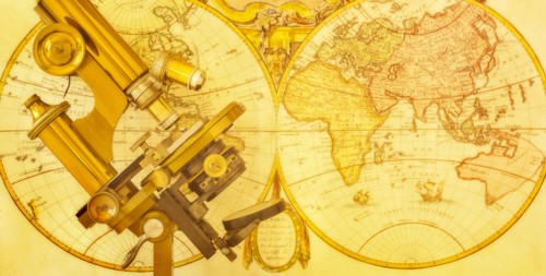 Old brass microscope against antique world map
