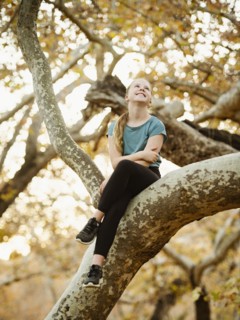 Girl sitting on tree branch