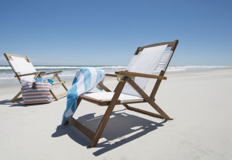 Empty beach chairs with bag and towel on beach