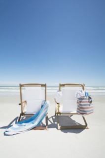 Empty beach chairs with bag and towel on beach