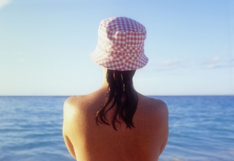 Rear view of woman in sunhat looking at sea
