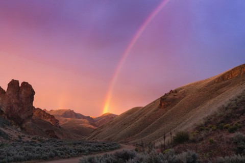 Rainbow above desert landscape at sunset