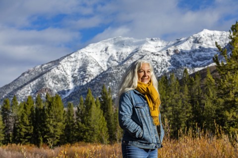 Smiling senior woman standing in autumn mountain landscape
