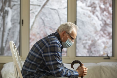 Senior man wearing protective mask sitting near window