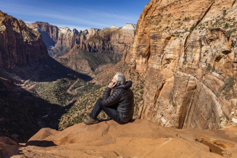 Senior man using phone at overlook of Zion Canyon in Zion National Park