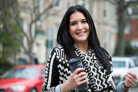Young woman carrying travel mug