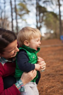 Laughing mother tickling son in park