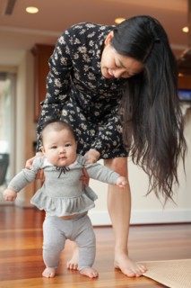 Mother helping baby girl to walk