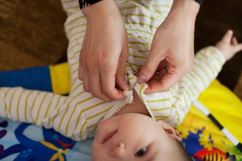 Close up of mother dressing baby daughter