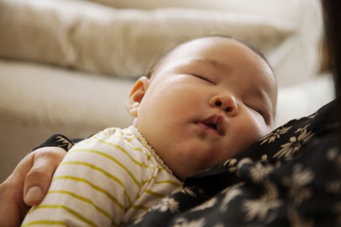 Close up of baby girl sleeping in mothers arms